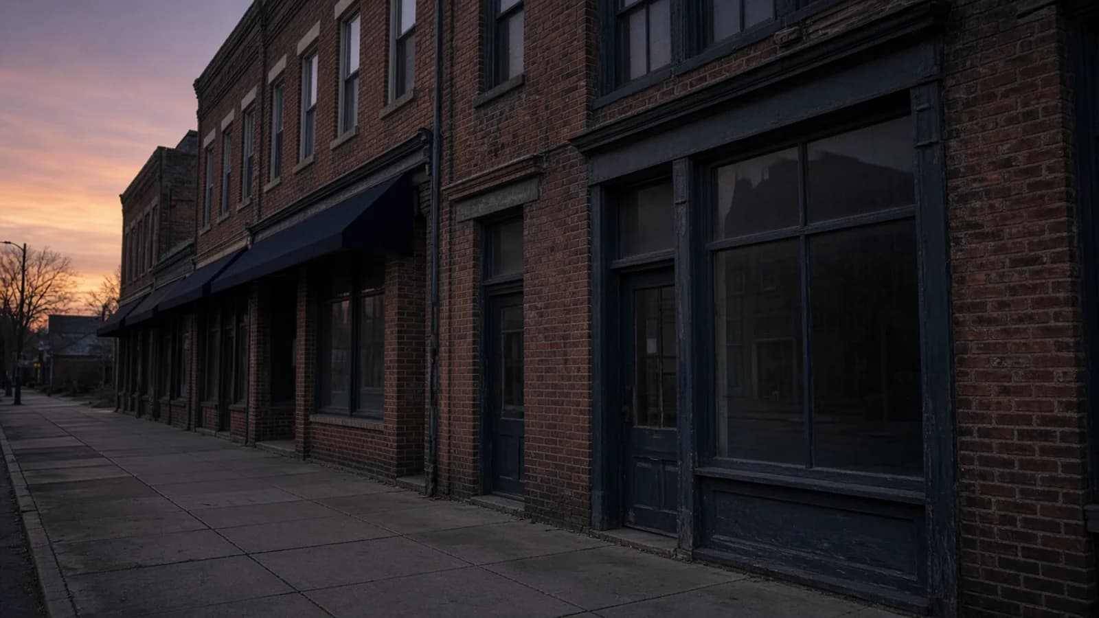 Small-town main street with low brick storefronts at dusk
